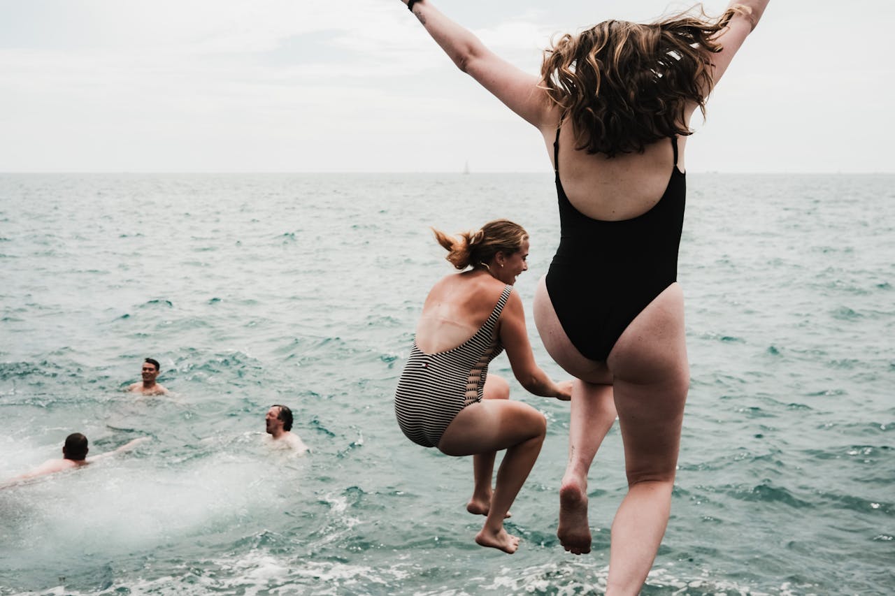 Friends enjoy a summer day by jumping into Lake Michigan, embodying fun and freedom.